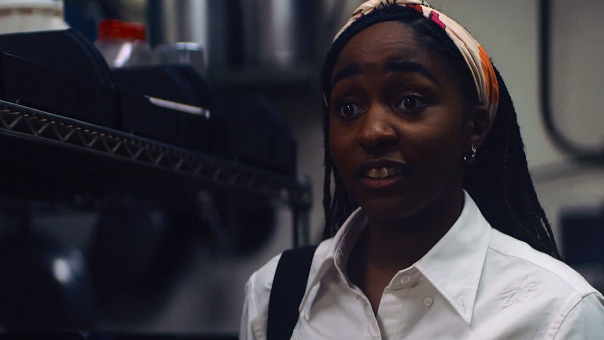 Sydney from The Bear FX show looking surprised with eyebrows raised in the kitchen and wearing a headband