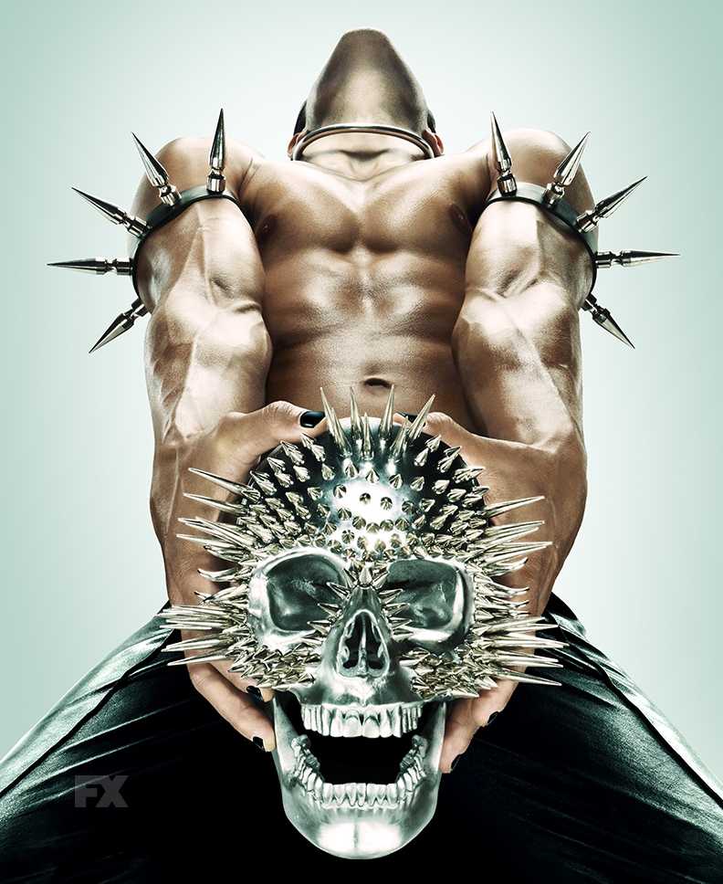 Man with black nail polish and black pants and spikes on arms clenching spiked metal skull from FX's AHS NYC