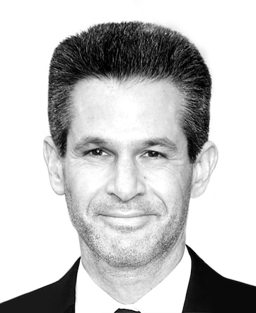 Simon Kinberg black and white headshot in black and white suit with plain white background