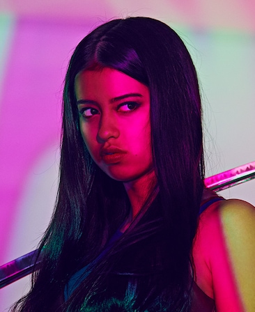 Amber Midthunder headshot with neon pink light covering face with light purple background, long sword hanging over shoulder 