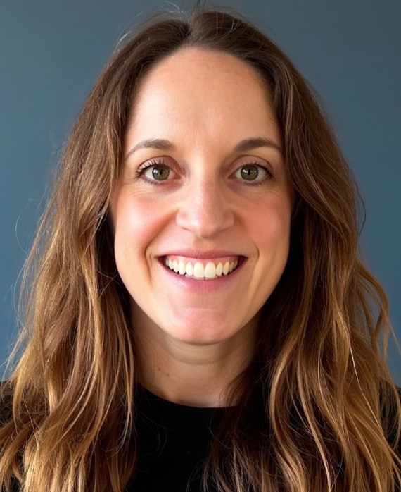 Headshot of executive producer Alicia Van Couvering, wearing a black tshirt with shoulder length brown golden hair.