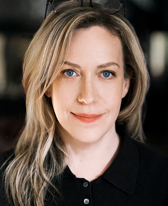 Headshot of executive producer Kim Rosenstock of FX's Love Story, wearing a black button up, and black framed glasses.