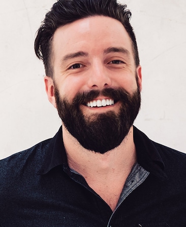 Nate Matteson headshot in black collared shirt with cream colored background