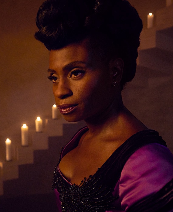 Adina Porter headshot in purple and black dress with candles on stairs from American Horror Story Apocalypse