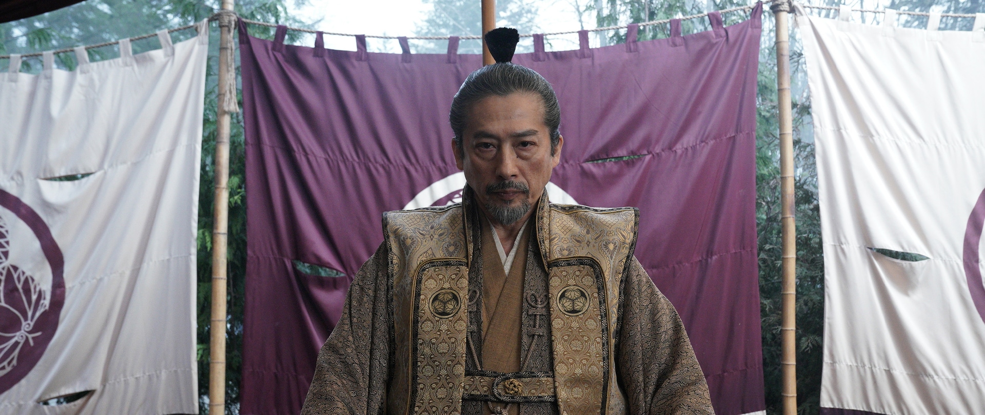 Close up of Toranaga sitting in front of a purple fabric in FX’s Shogun