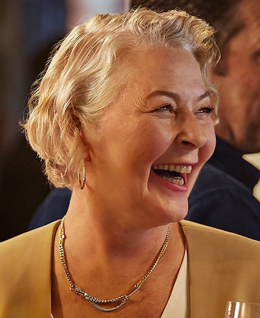 Stella Gonet headshot wearing a silver chain necklace and a beige top