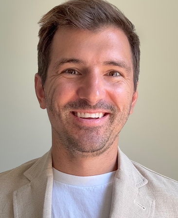 Headshot of executive producer Eric Kovtun of FX's Love Story, wearing white tshirt and beige suit.