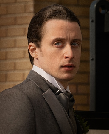Rory Culkin headshot wearing a suit and standing by a brick wall