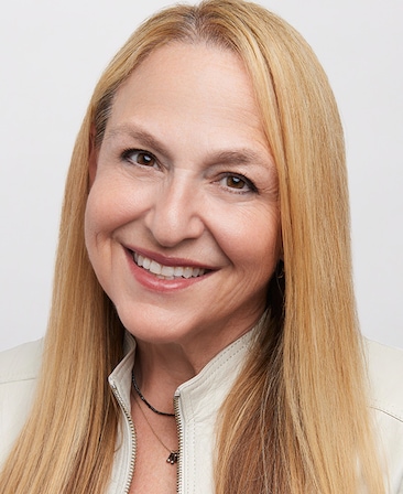 Headshot of executive producer Monica Levinson of FX's Love Story, wearing a white suede jacket.