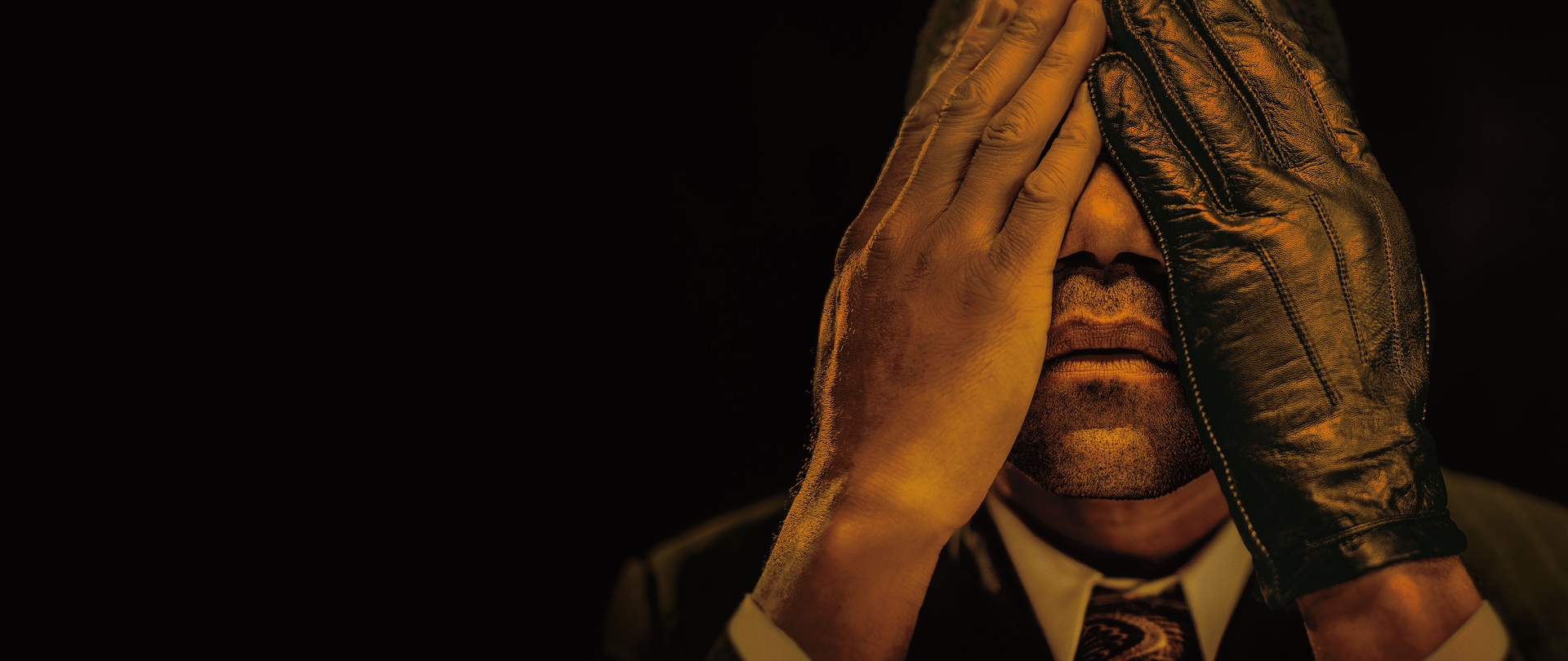 Cuba Gooding Jr portraying OJ Simpson and covering eyes with his hands, but one hand is wearing a black leather glove