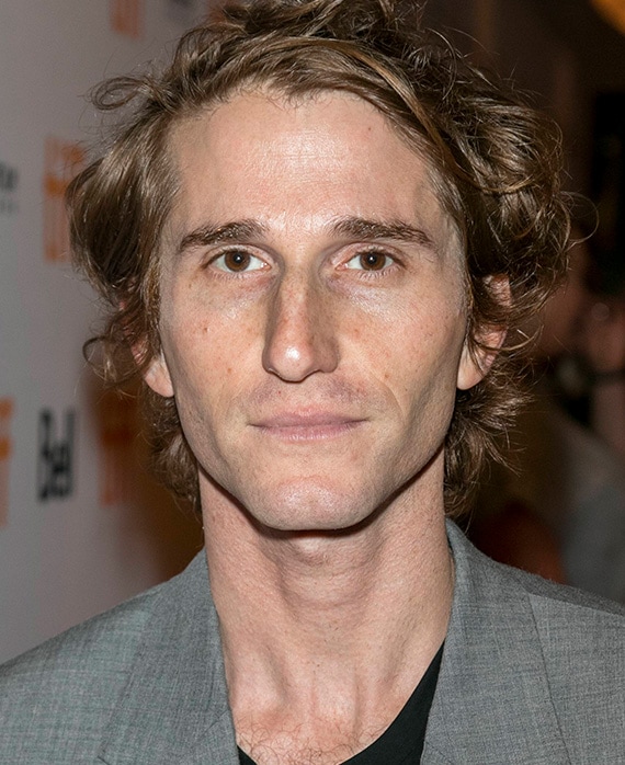 Headshot of executive producer Max Winkler of FX's Love Story, wearing a black shirt and grey suit.