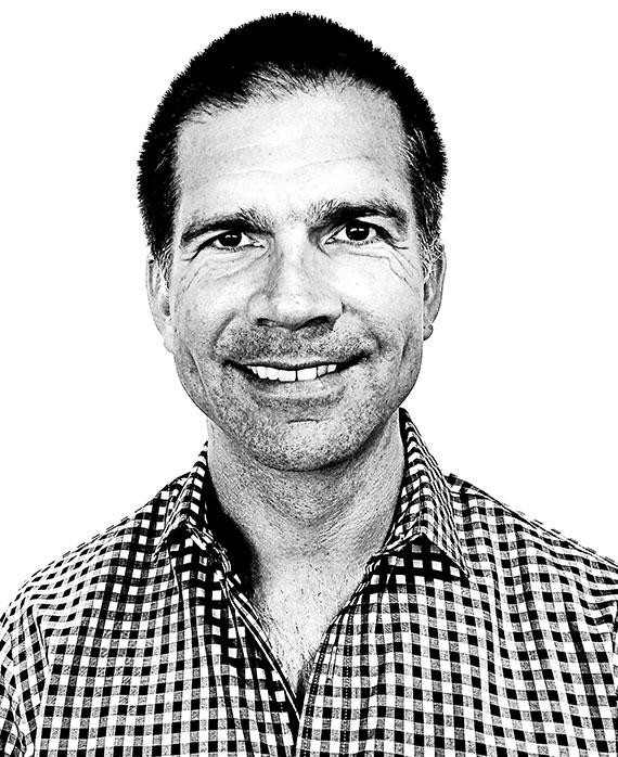 Paul Young headshot wearing a plaid button up shirt