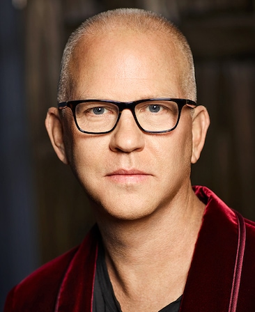Headshot of executive producer Ryan Murphy of FXs Love Story wearing a red velvet jacket, with black framed glasses.