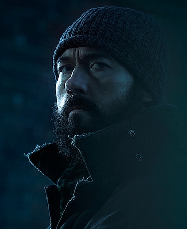 Kevin Durand Headshot wearing a beanie and black coat