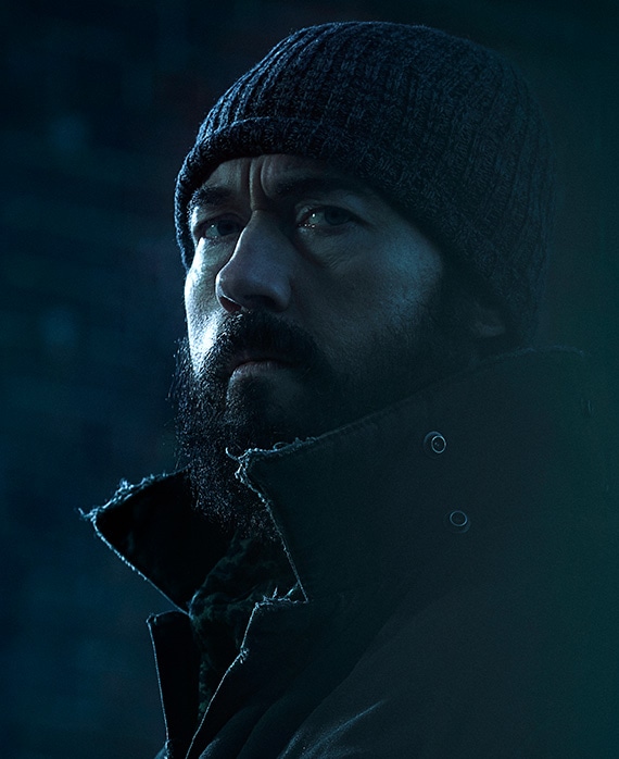 Kevin Durand Headshot wearing a beanie and black coat