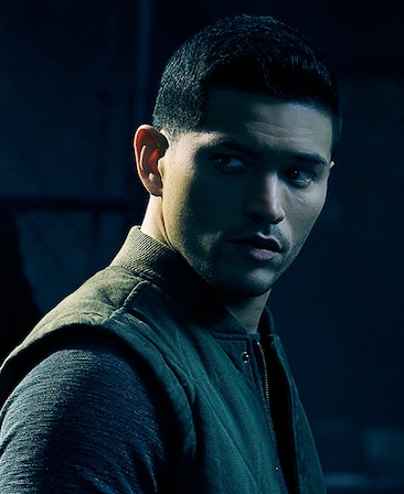 Miguel Gomez Headshot wearing a vest and turning his head to the side 