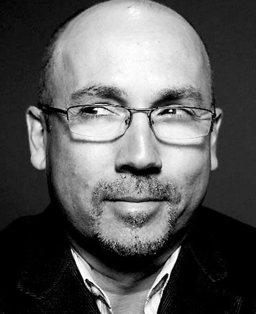J. Miles Dale Headshot wearing glasses with a black and white filter