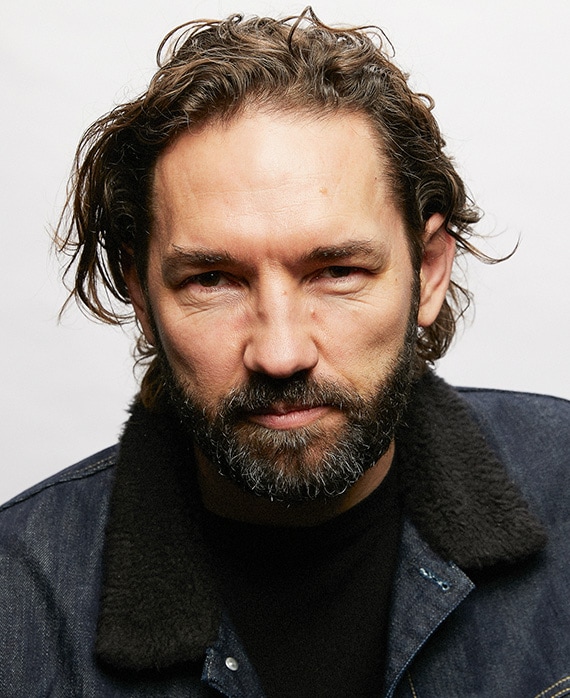 Nash Edgerton headshot wearing a black shirt and denim jacket