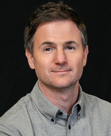 Ryan Fleck headshot wearing a gray button up shirt