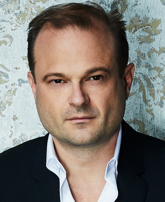 Brad Simpson headshot wearing a white shirt with black jacket