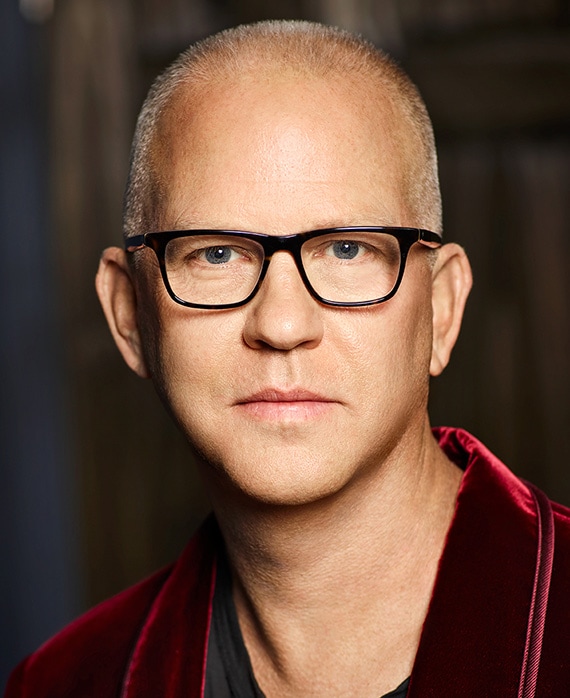 Ryan Murphy headshot wearing a red jacket and black glasses