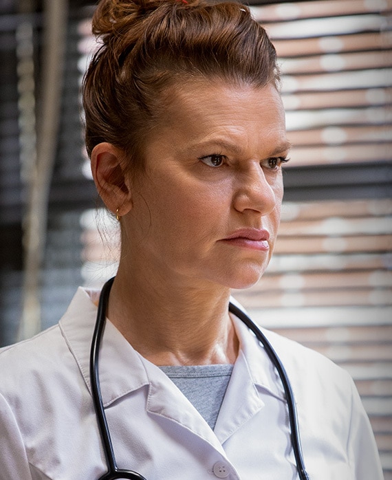 Sandra Bernhard headshot wearing a white shirt and black stethoscope around neck 