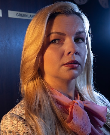 Amber Tamblyn headshot wearing a patterned jacket and pink scarf around her neck