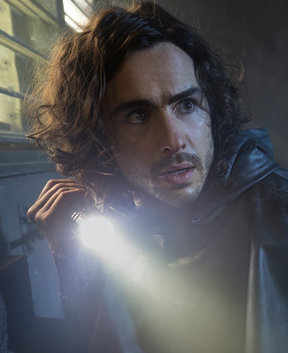 Ben Schnetzer headshot holding a flash light and wearing a black top