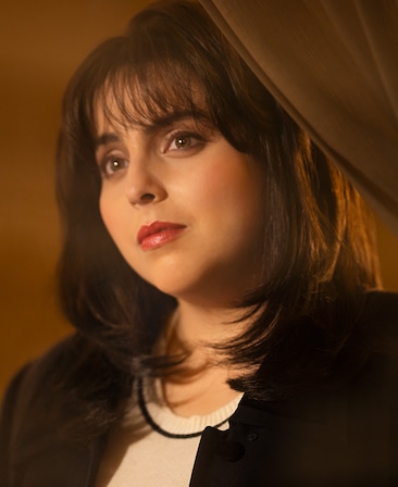 Headshot of Beanie Feldstein as Monica Lewinsky in American Crime Story behind drape