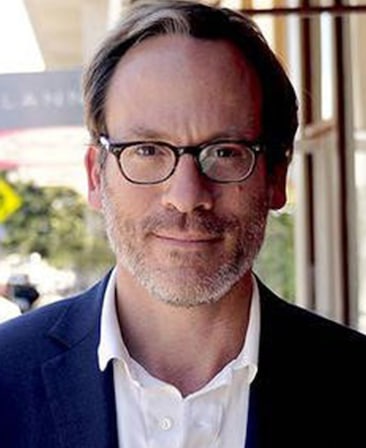 Michael Costigan headshot wearing a white shirt, jacket suit jacket and glasses