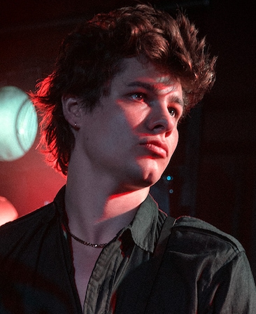 Toby Wallace headshot wearing a black shirt and necklace