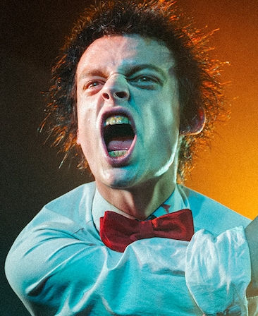 Anson Boon headshot wearing a white shirt and red bow tie