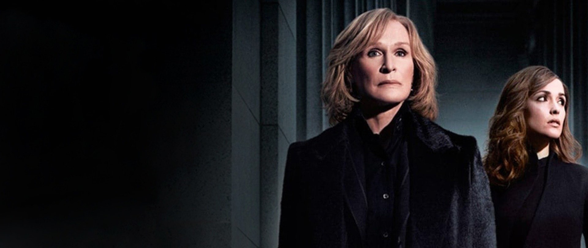 Litigator Patty Hewes and Ellen Parsons wearing black suits standing in a dark entryway with court hall stone pillars