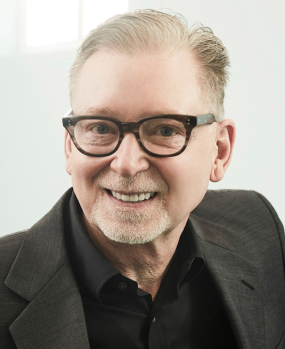 Warren Littlefield headshot wearing a black suit and glasses against a white background