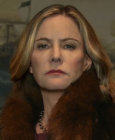 Jennifer Jason Leigh headshot wearing a fur coat and chain necklace