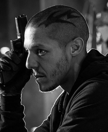 Theo Rossi headshot holding a gun and a tattoo on his head