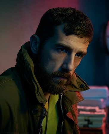 Carter Hudson headshot wearing a green jacket and green shirt