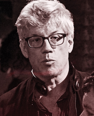 Leslie Tolan headshot wearing a black jacket and black glasses