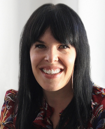 Alexis Martin Woodall headshot wearing a red patterned shirt standing in front of a white background