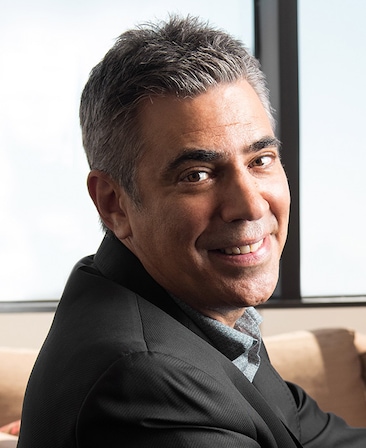 Michael London Headshot wearing a black suit jacket and sitting by a window
