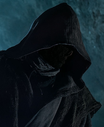 Kurt Sutter headshot in obscured black cloak and robe, in dark cave and rocks illuminated by moonlight 