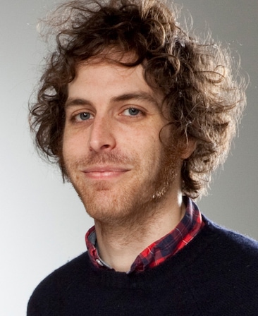 Headshot of executive producer Jonathan Krisel, wearing a red plaid shirt with a deep blue sweater over it.