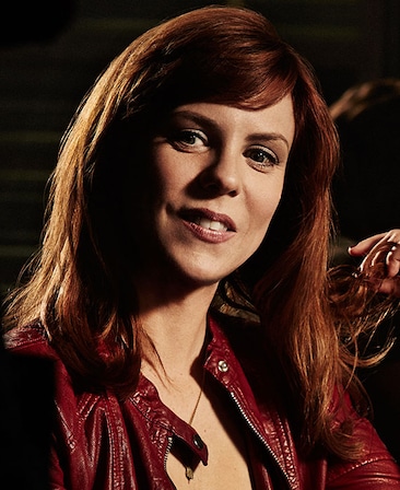Sarah Burns headshot wearing a red leather jacket