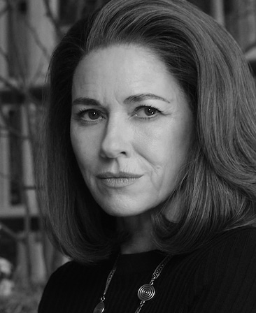 Headshot of Naomi Watts as Jackie Kennedy in FX's Love Story in a black sweater and long necklace.